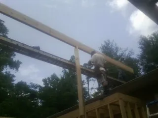 Carpenter setting a ridge beam over a new addition frame — Ice Dam Removal by Roofing Brothers in Eutaw