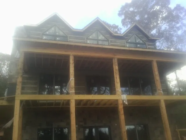 Dormers and porch framing on a large log home under construction — Roof Coating work by our crew in Eutaw