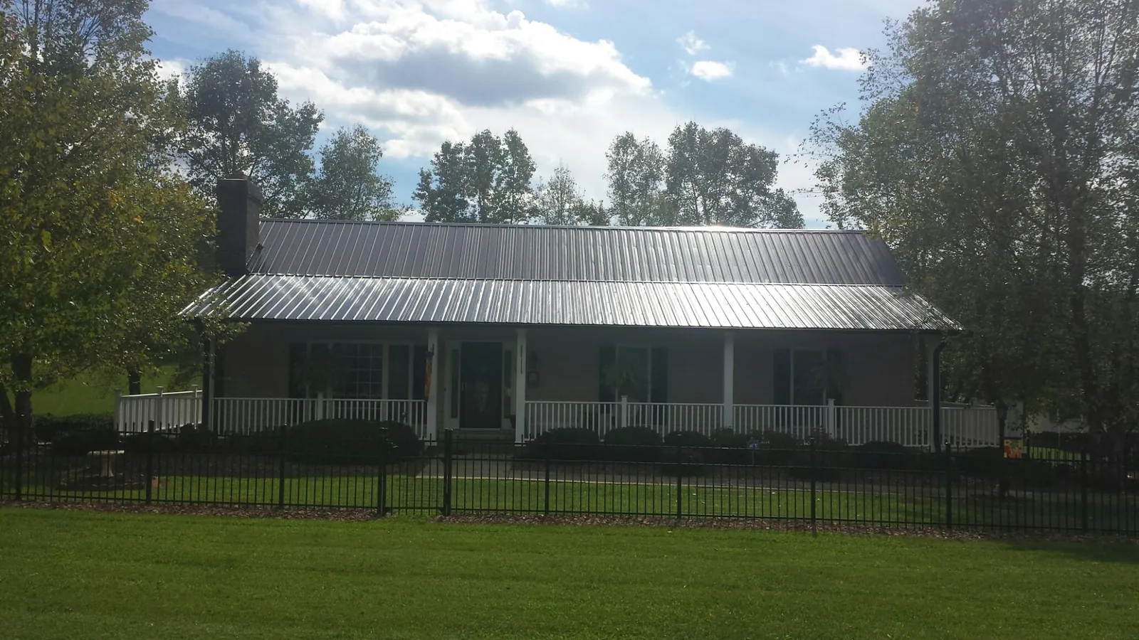 Gray metal roof on a brick ranch with a full width front porch — Gutter Guard Installation work by our crew in Eutaw