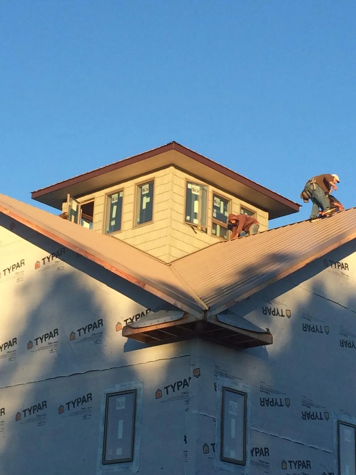 Roofers working around a rooftop cupola on a new metal roof at sunset — Roof Waterproofing in Eutaw by Roofing Brothers
